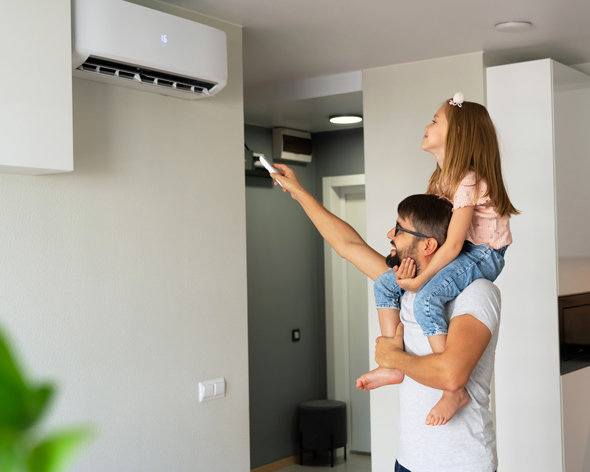 father with young daughter on shoulders turn on air conditioner using remote control, adjusting temperature